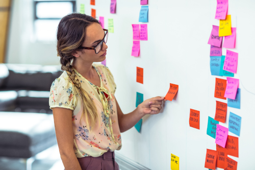 Woman arranging sticky notes on an office whiteboard
