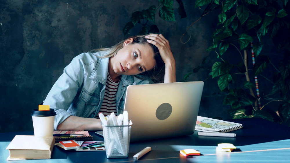 Woman with a laptop appears overworked and stressed out
