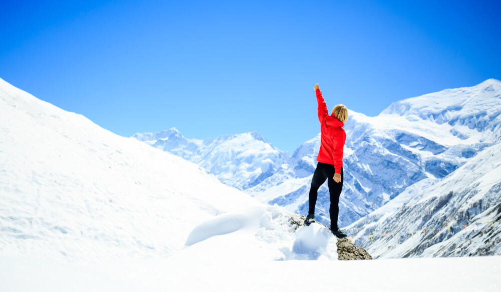 A woman summits a high mountain