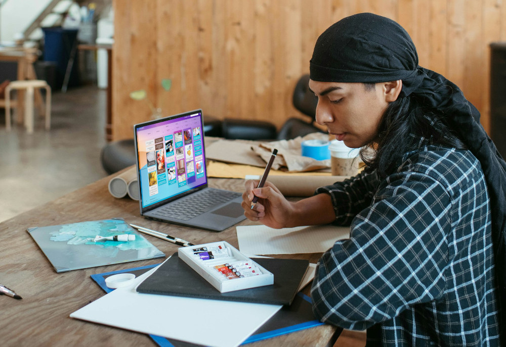 Designer working with paper drawings and a ditial Kanban Tool board.