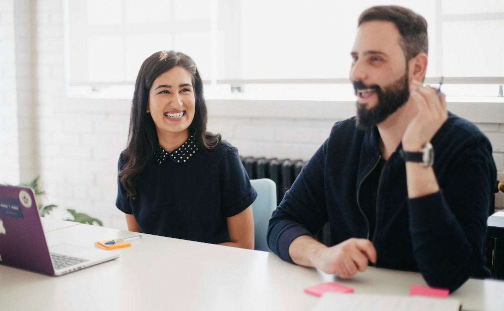 Team members smiling content at a conference desk