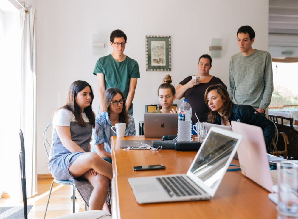 A team groups in front of a laptop to discuss things together