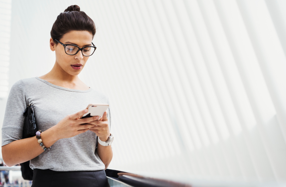 A stressed woman focuses on her smartphone while walking